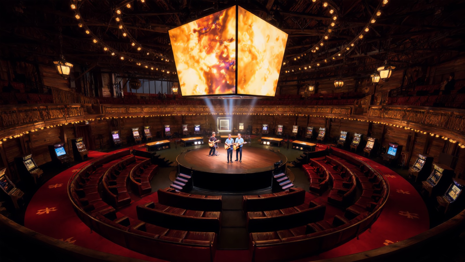 Concept render — the hero: a live band on the round center stage beneath the hanging four-sided jumbotron, lounge tiers and machine rings wrapping the warm timber hall