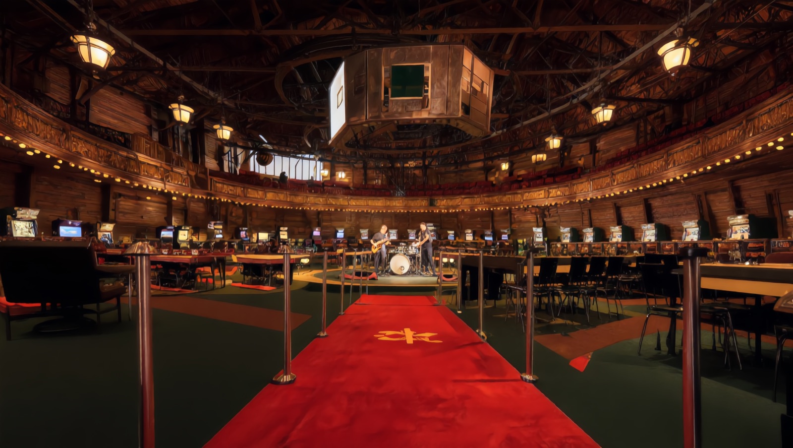 Concept render — down the red river lane: machines flanking the carpet, the band on the round stage ahead beneath the hanging jumbotron